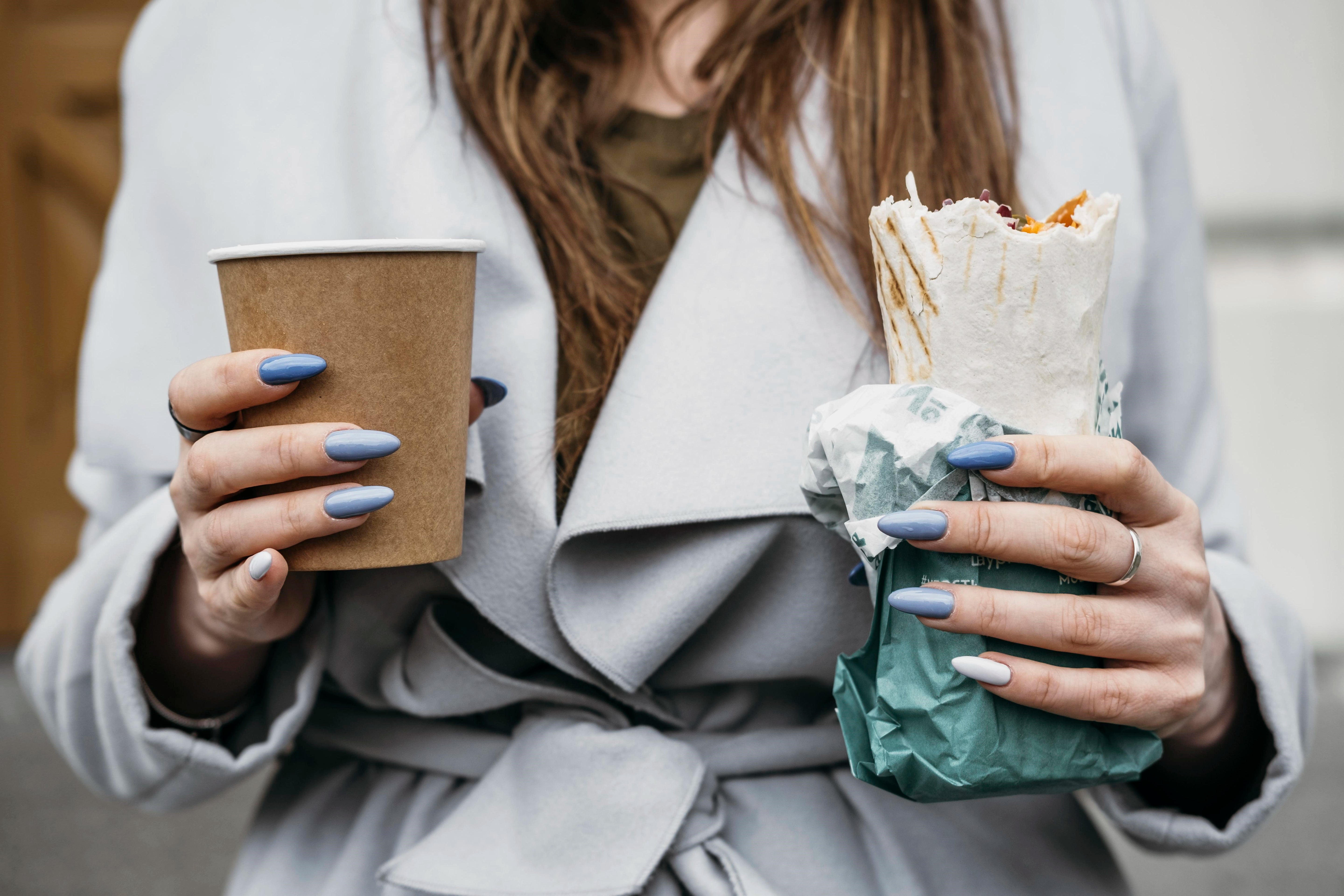 Frau mit Pappbecher und Wrap in Seidenpapier eingewickelt.
