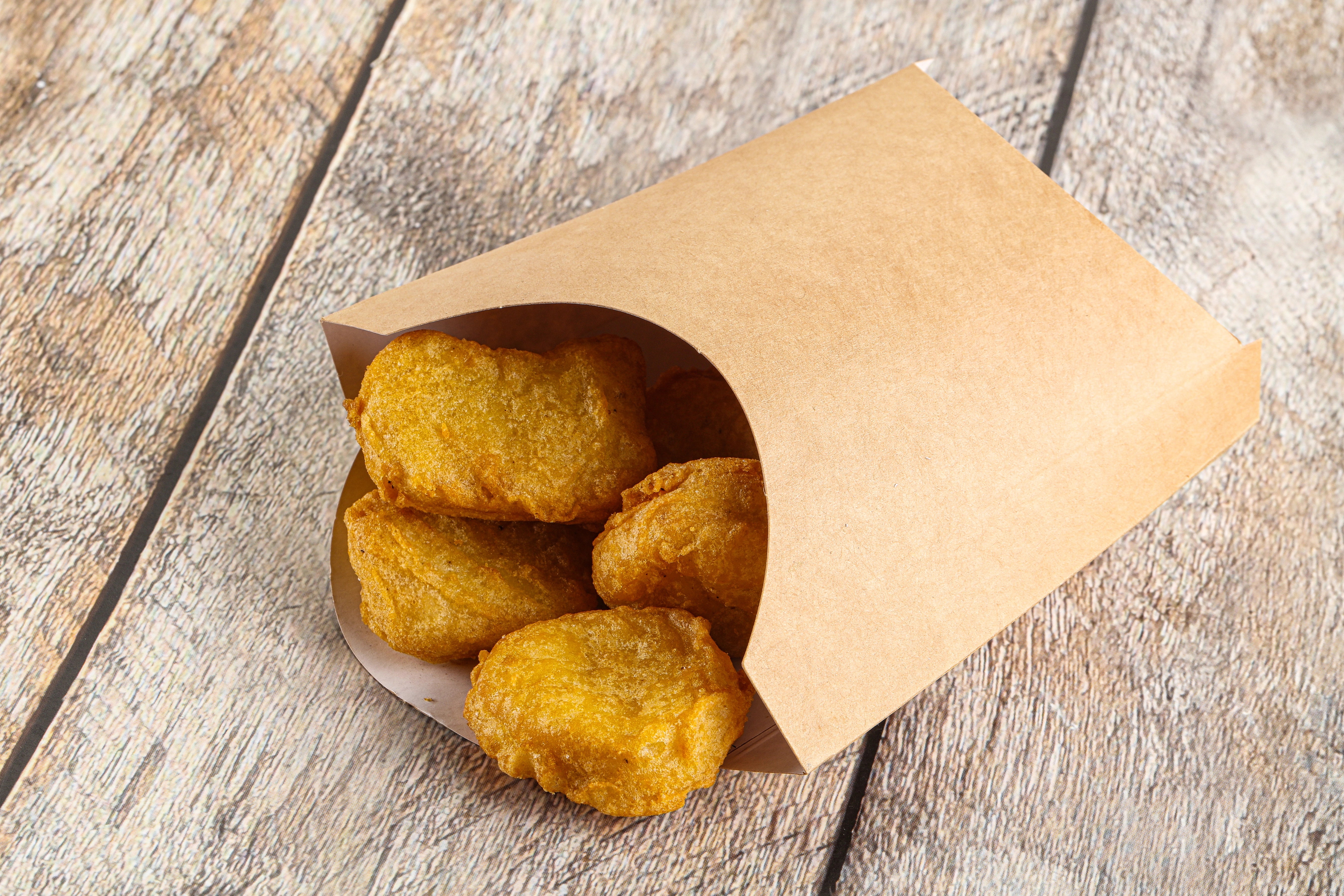 Knusprige Chicken Nuggets in einem kleinen, braunen Warmhaltebeutel.