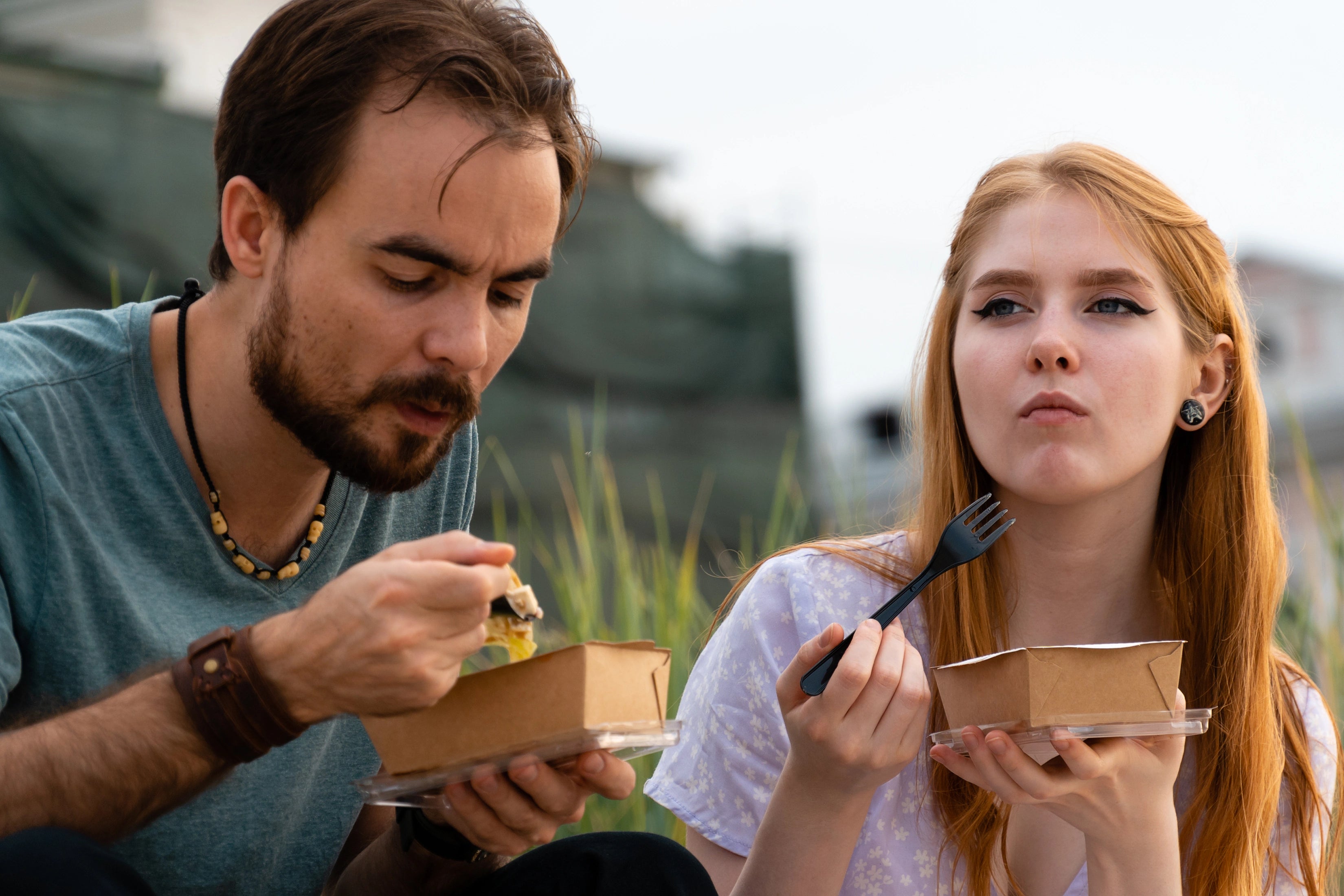 Mann und Frau genießen Take Away Speisen aus nachhaltigen Menüschalen mit Deckel.