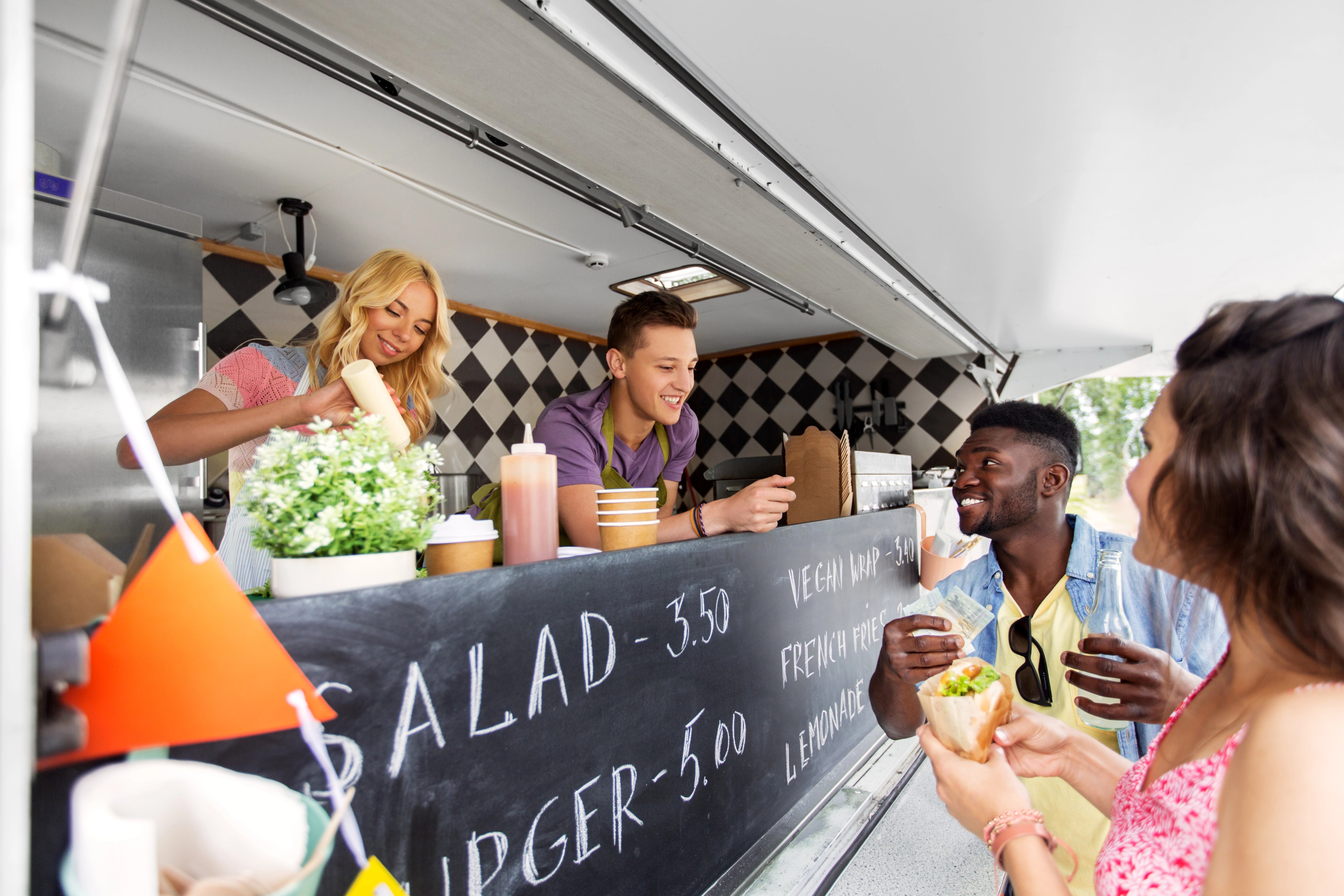 Glückliche Kunden und Verkäufer bei einem Food Truck.