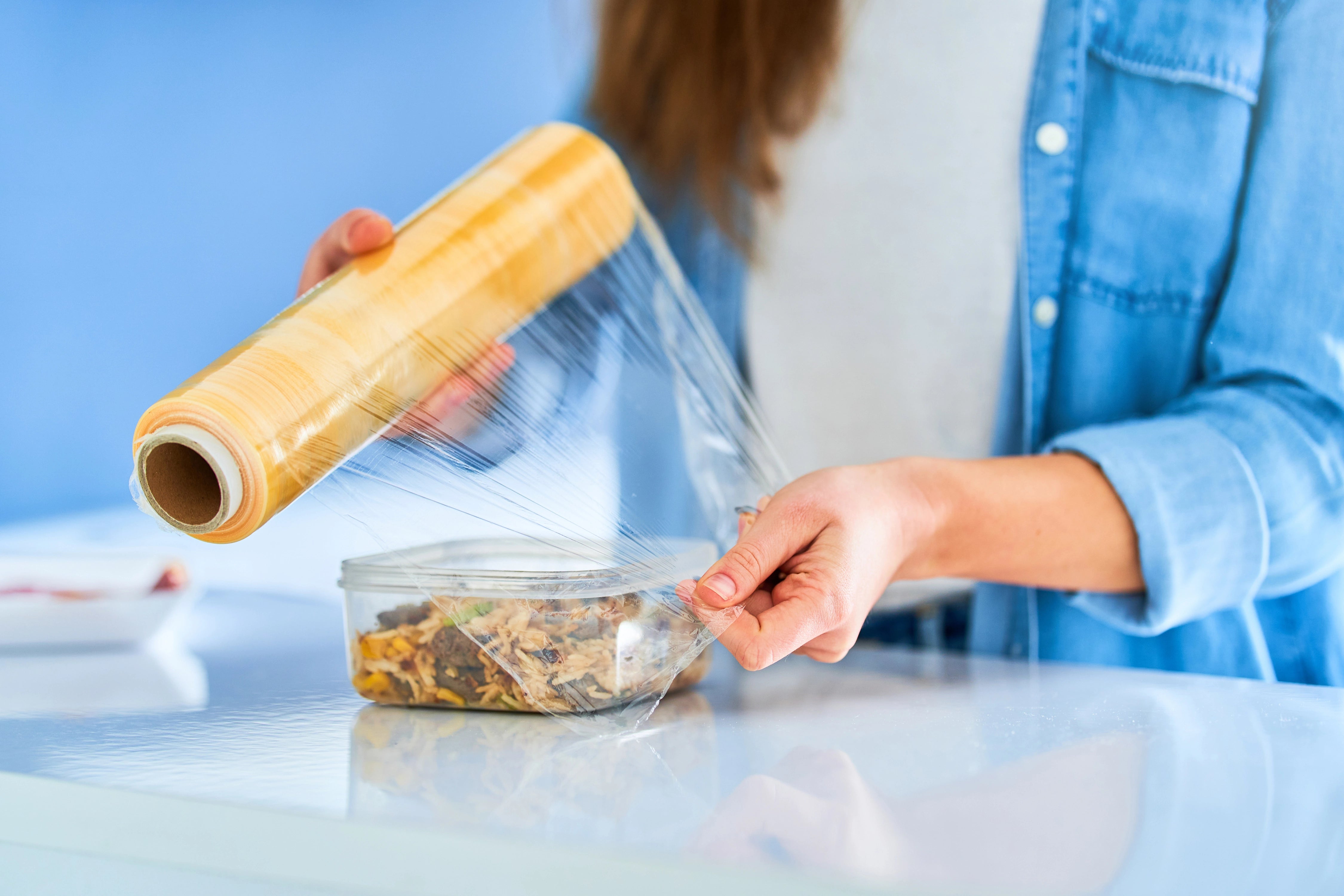 Frau verpackt frisches Essen mithilfe von Zellglasfolie.