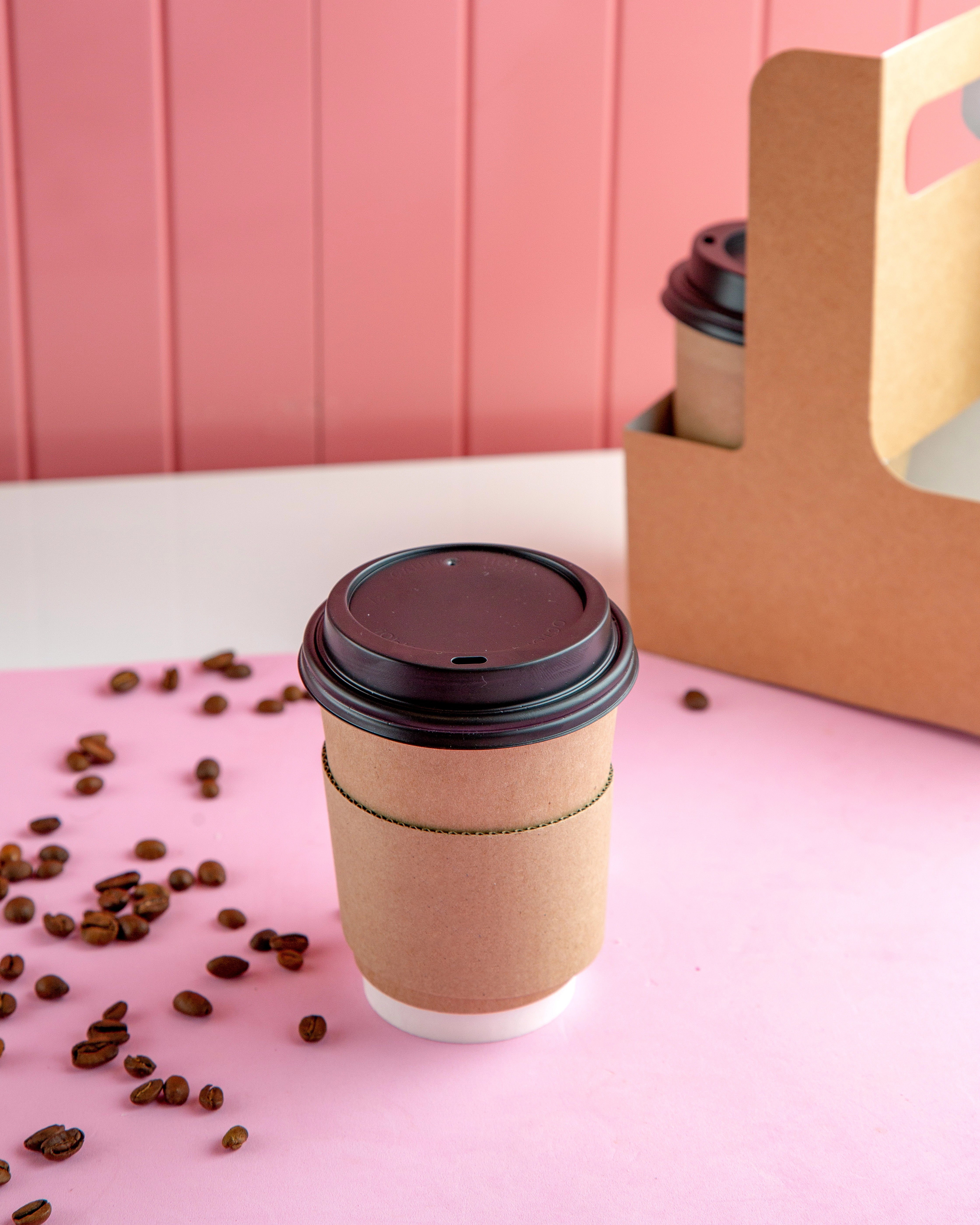 Take Away-Kaffeebecher und Kaffeebohnen auf einem Tisch.