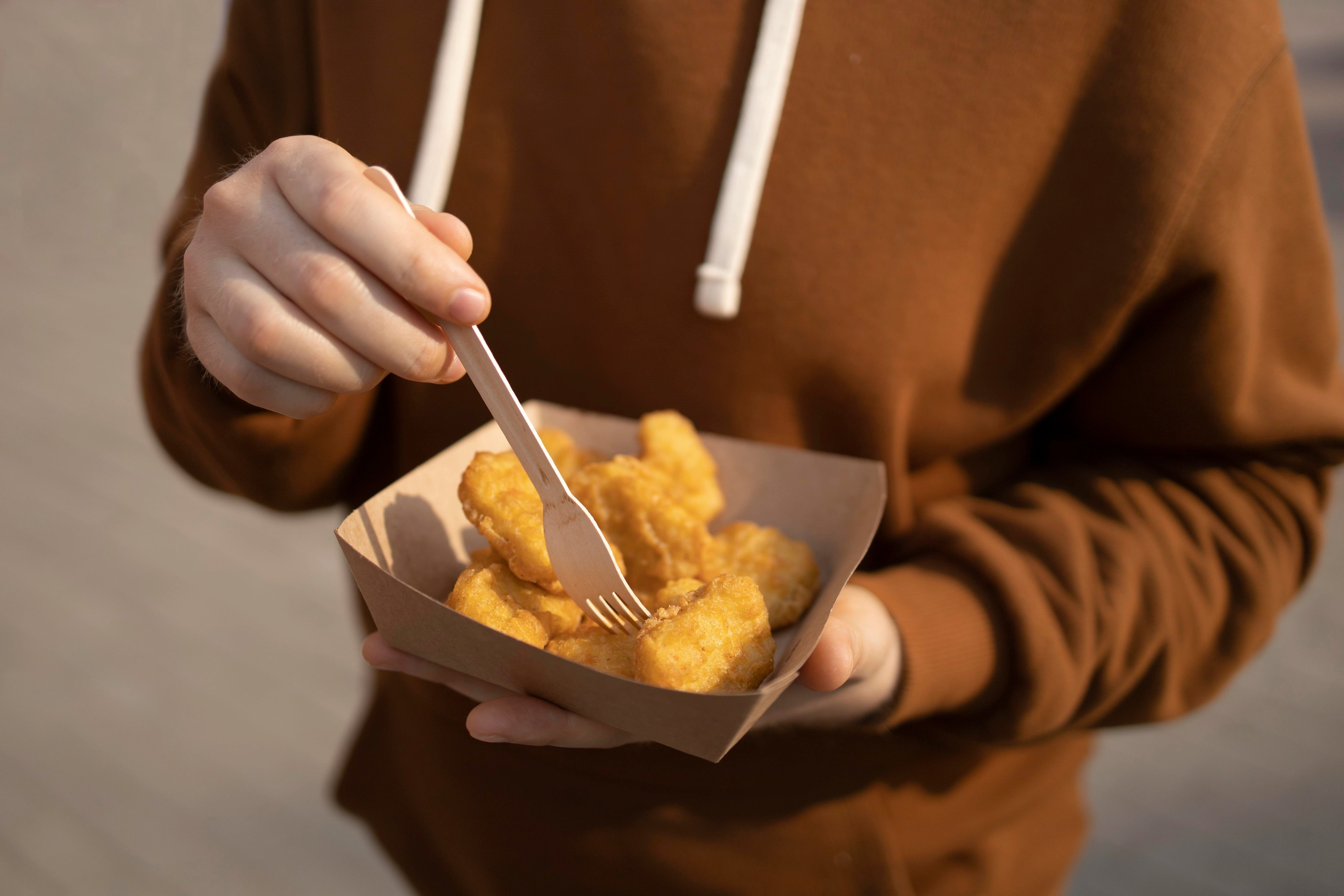 Chicken Nuggets, die gerade mit einer Holzgabel gegessen werden.