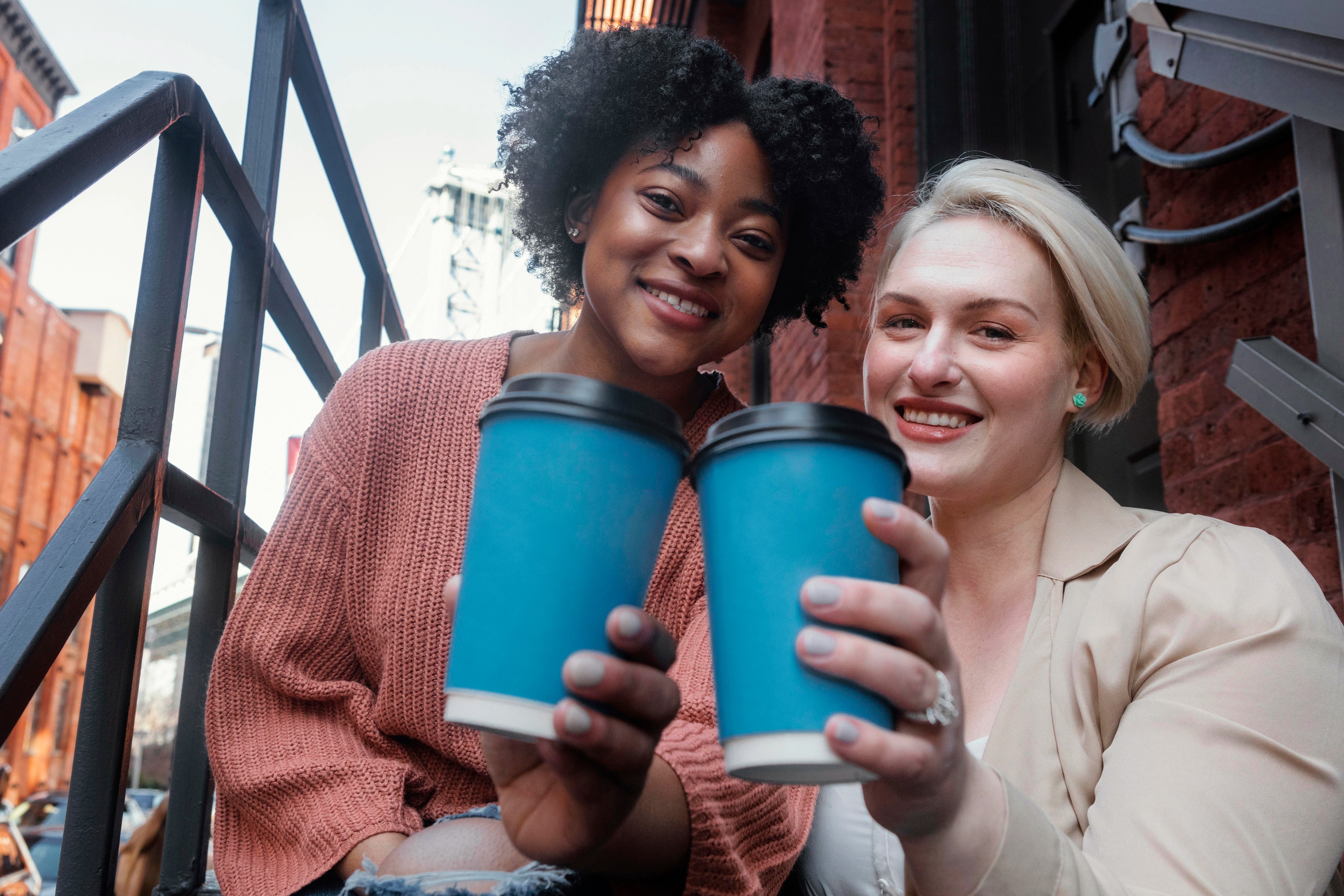 Zwei Frauen in der Stadt mit wiederverwendbaren Trinkbechern.