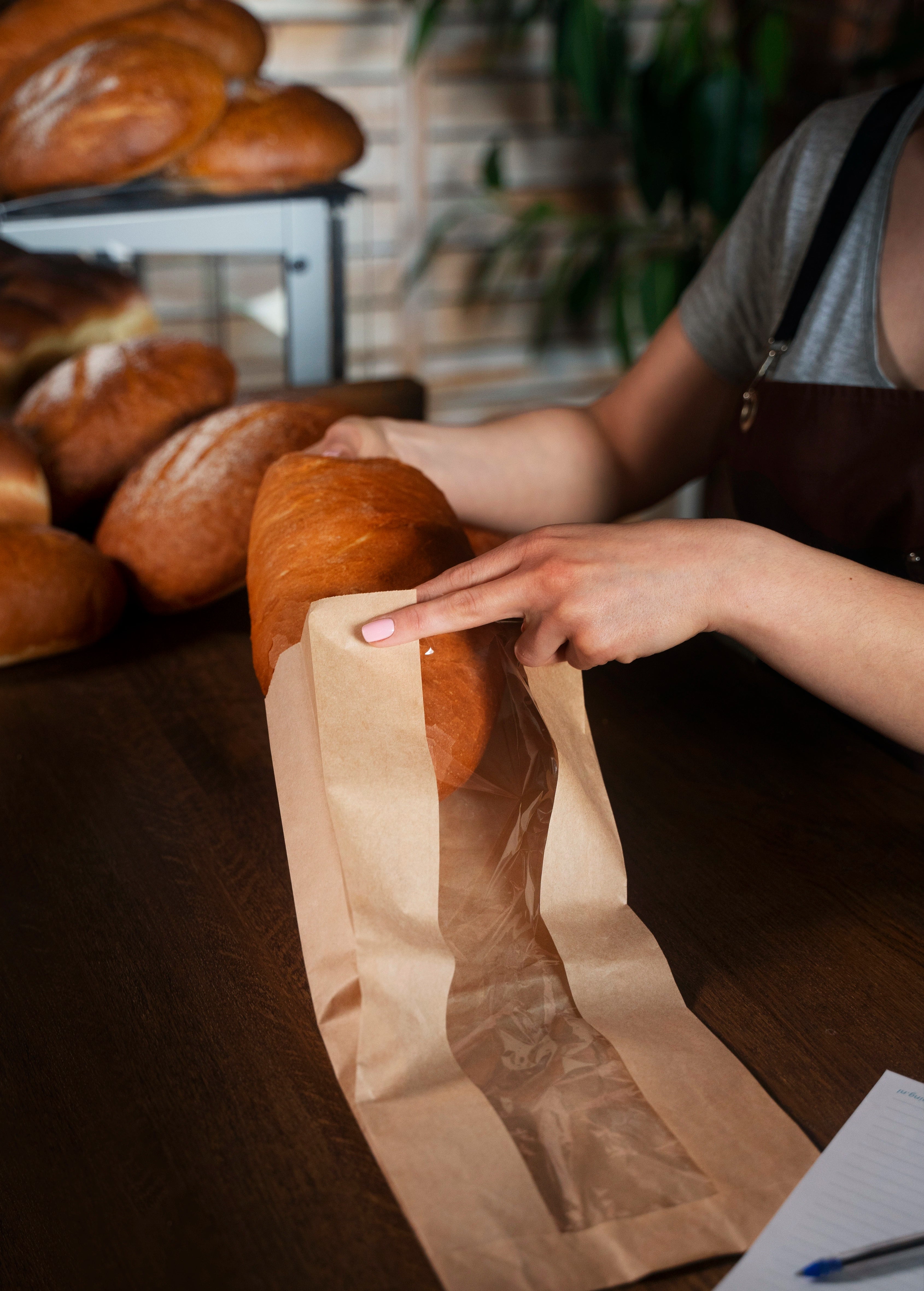 Bäckerin, die Brot in einen Bäckerfaltenbeutel mit Sichtfenster packt.