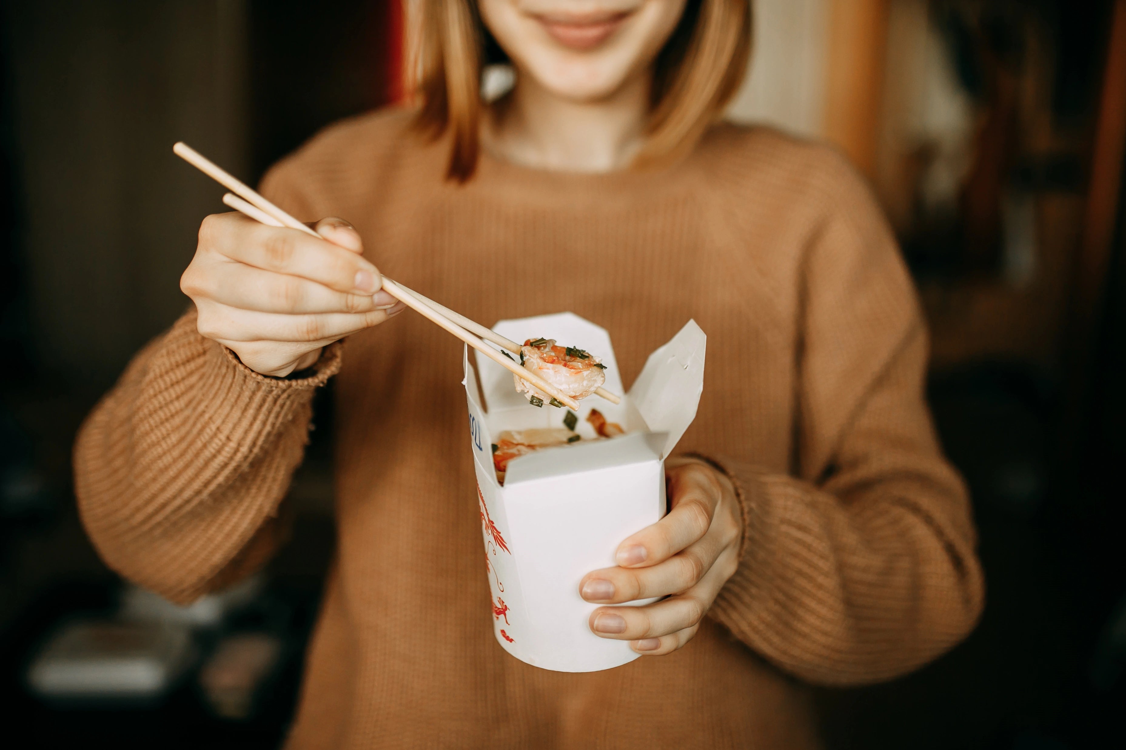 Frau präsentiert asiatisches Essen aus einer klassischen Asia Box.